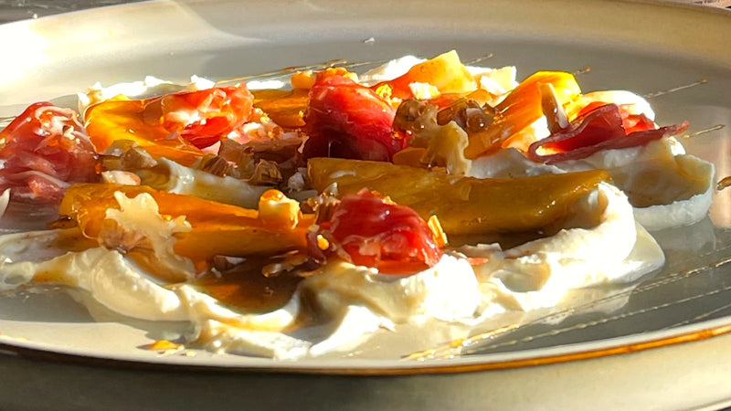 Plato salado con base cremosa, verduras asadas, jamón crudo, nueces y un hilo de miel por encima