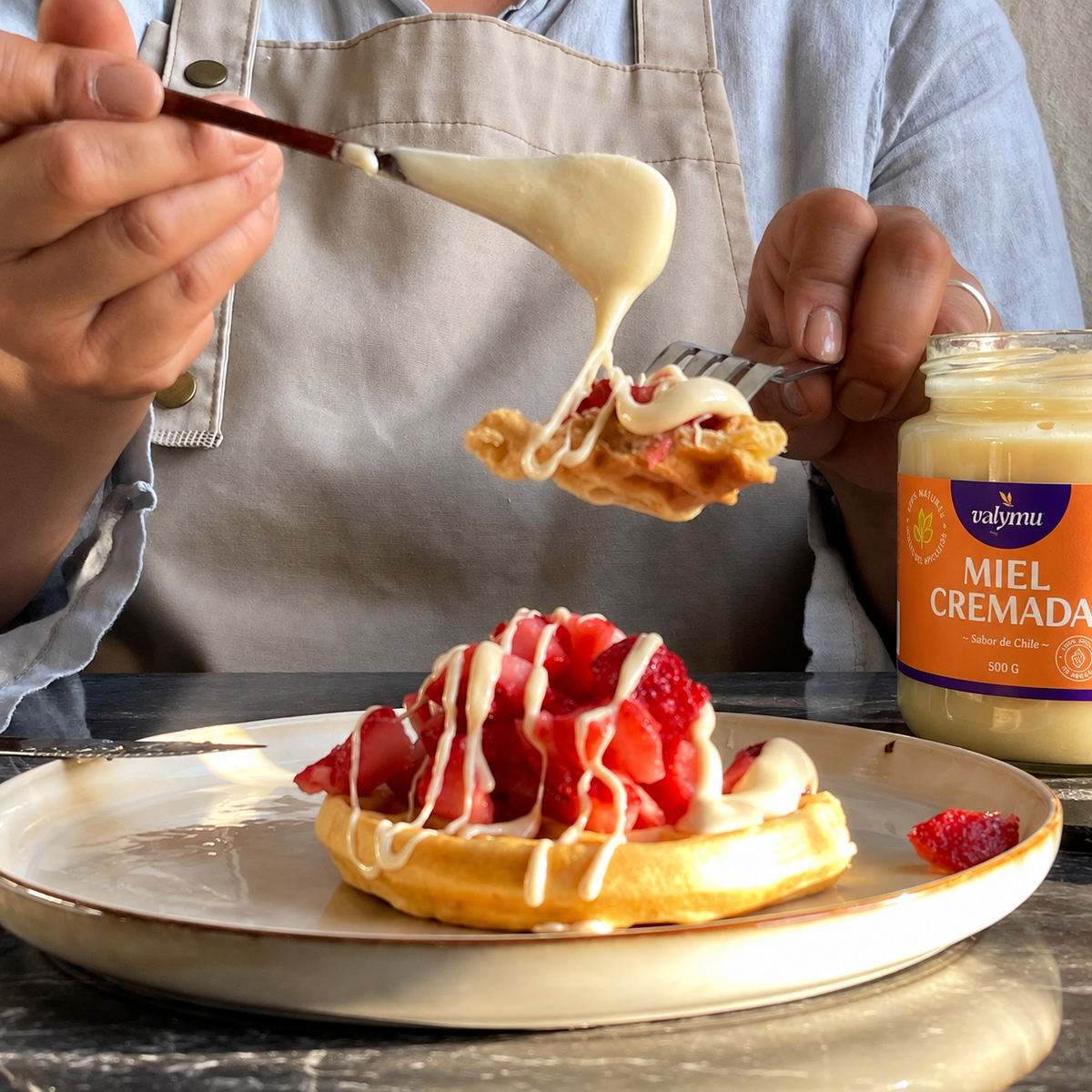 Miel cremada de quillay Valymu sobre waffle con frutillas, junto al frasco con la nueva etiqueta